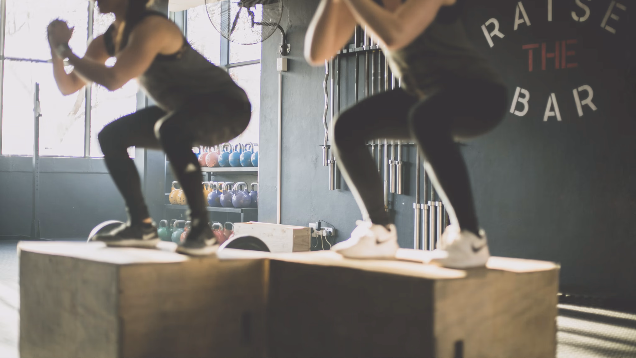 Athletes performing box jumps in a strength training gym